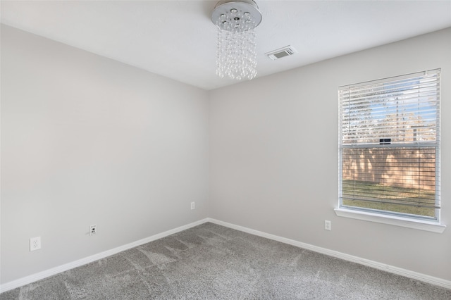 empty room with carpet flooring, a chandelier, and a wealth of natural light