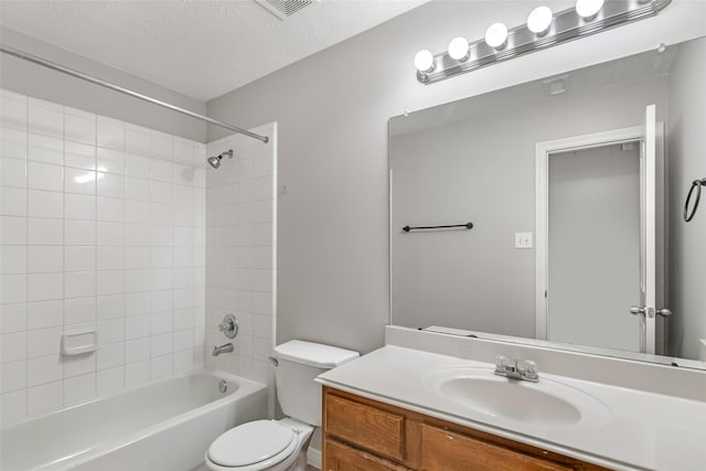 full bathroom with vanity, toilet, a textured ceiling, and tiled shower / bath combo