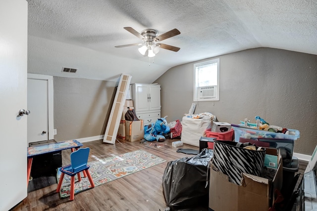 additional living space featuring cooling unit, vaulted ceiling, hardwood / wood-style flooring, ceiling fan, and a textured ceiling