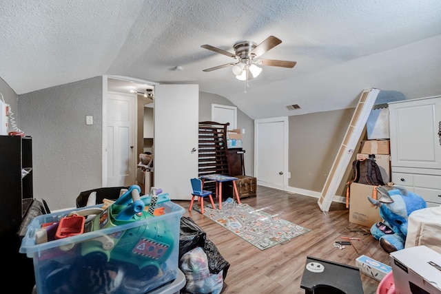 interior space with a textured ceiling, ceiling fan, hardwood / wood-style floors, and lofted ceiling