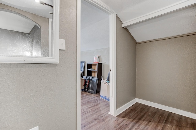 hall with wood-type flooring and vaulted ceiling