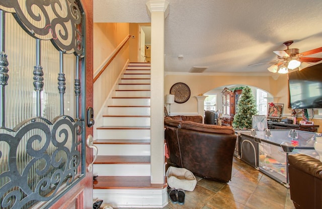 entrance foyer with ceiling fan, crown molding, and a textured ceiling