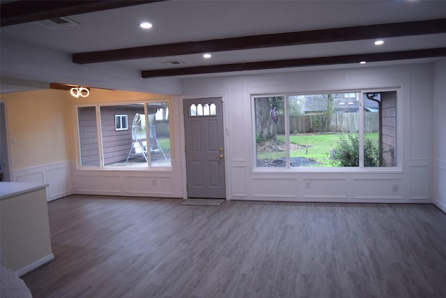 foyer entrance with beamed ceiling, wood-type flooring, and a wealth of natural light