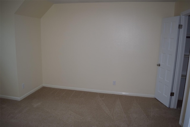 carpeted empty room with vaulted ceiling