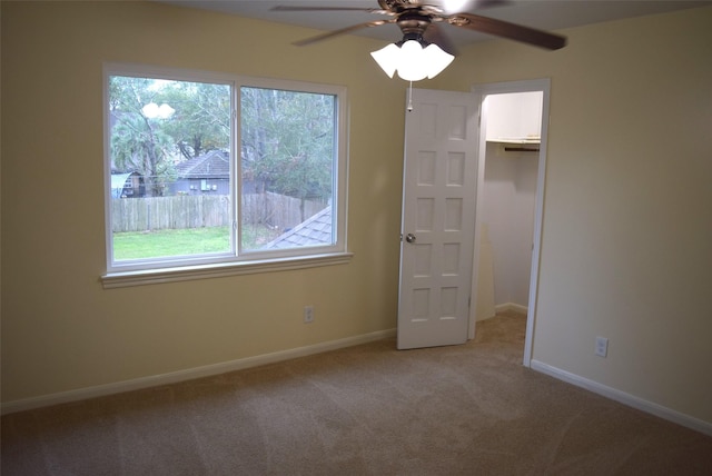 unfurnished bedroom featuring ceiling fan, a walk in closet, light carpet, and a closet