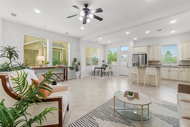 tiled living room featuring beam ceiling, ceiling fan, and a healthy amount of sunlight