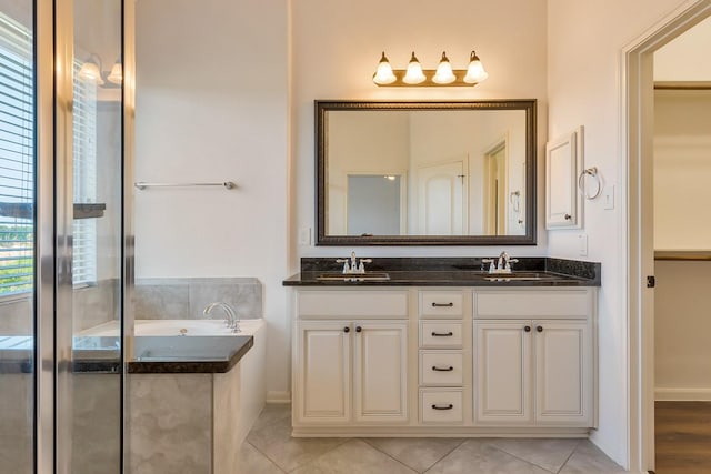 bathroom with tile patterned flooring, vanity, and a bath