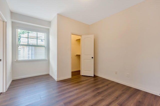 unfurnished bedroom with dark hardwood / wood-style flooring, a spacious closet, and a closet