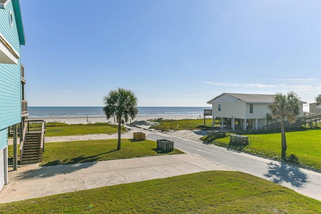 view of property's community featuring a lawn, a water view, and a view of the beach