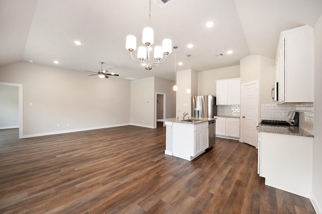 kitchen featuring appliances with stainless steel finishes, tasteful backsplash, vaulted ceiling, decorative light fixtures, and an island with sink