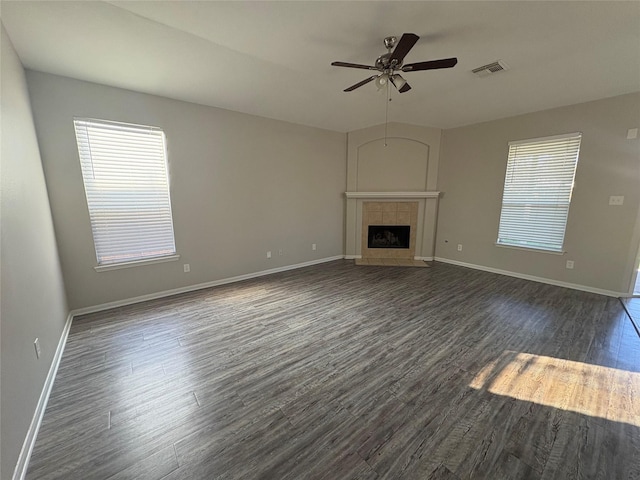 unfurnished living room featuring a tile fireplace, dark hardwood / wood-style floors, and ceiling fan