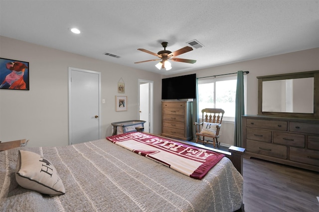 bedroom with a textured ceiling, ceiling fan, and dark wood-type flooring