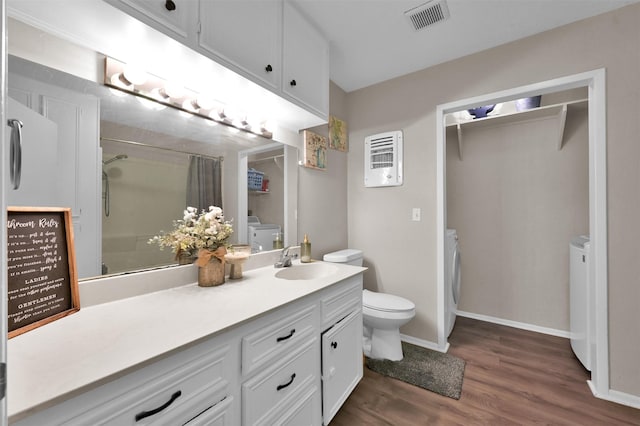 bathroom with walk in shower, vanity, wood-type flooring, independent washer and dryer, and toilet