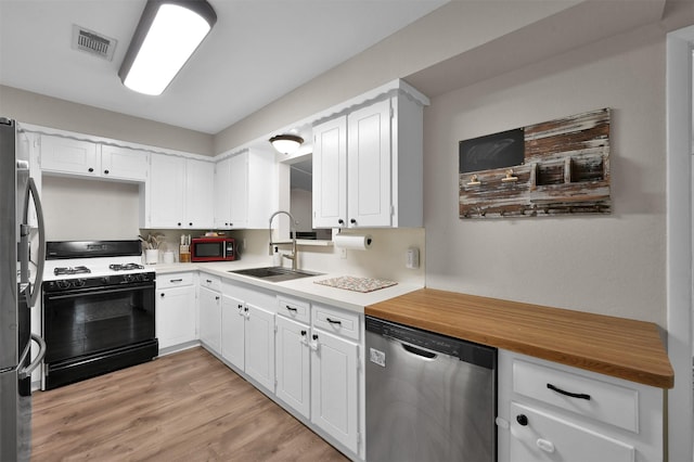 kitchen with sink, white cabinets, black appliances, and light wood-type flooring