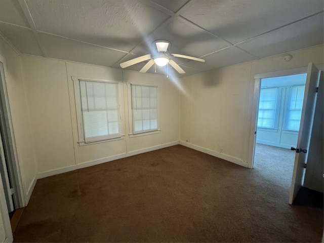 unfurnished room with ceiling fan and dark carpet