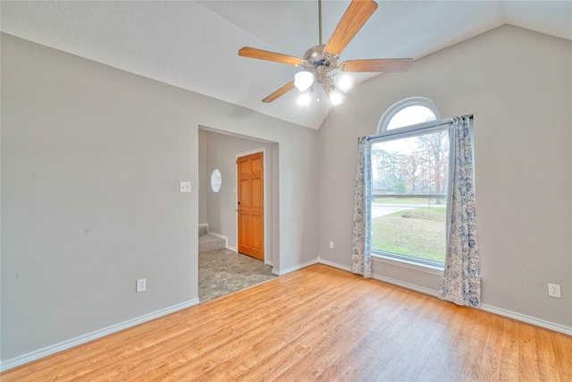 spare room with vaulted ceiling, ceiling fan, and light hardwood / wood-style flooring