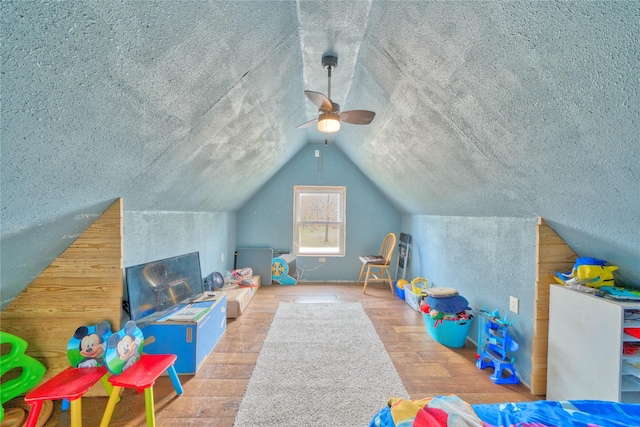 rec room with wood-type flooring, lofted ceiling, and a textured ceiling