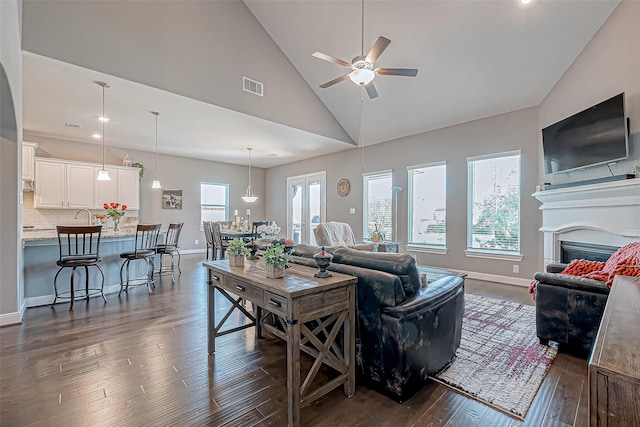 living room featuring ceiling fan, dark wood-type flooring, and a wealth of natural light