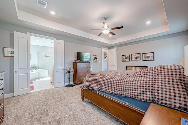 bedroom with a raised ceiling, ensuite bath, ceiling fan, and carpet