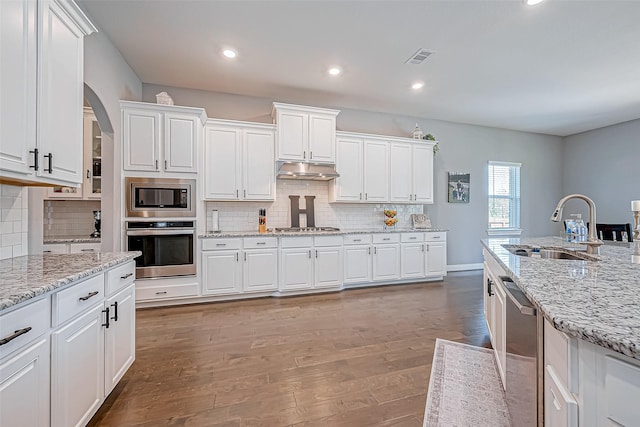 kitchen featuring white cabinets, sink, hardwood / wood-style flooring, light stone countertops, and stainless steel appliances