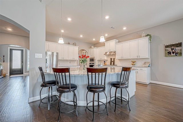 kitchen featuring white cabinets, pendant lighting, stainless steel appliances, and an island with sink