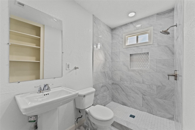 bathroom with toilet, sink, and a tile shower