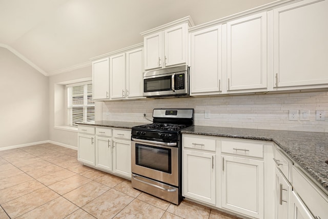 kitchen with dark stone countertops, white cabinets, stainless steel appliances, and vaulted ceiling