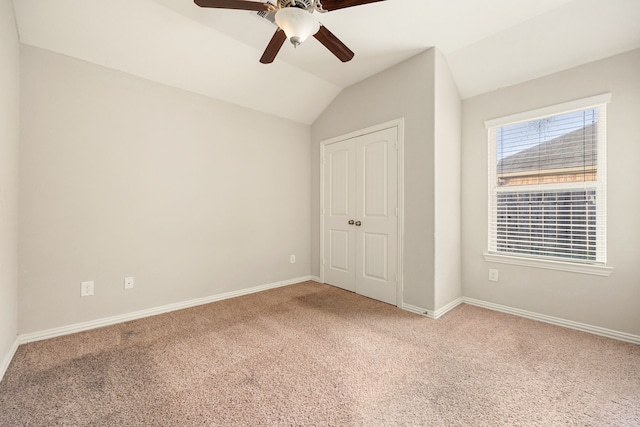 unfurnished bedroom with carpet, ceiling fan, a closet, and vaulted ceiling