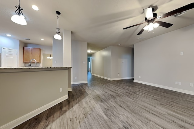 unfurnished living room with ceiling fan, dark wood-type flooring, and sink