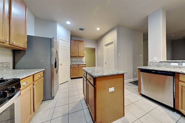 kitchen featuring light stone countertops, light tile patterned floors, stainless steel appliances, and a kitchen island