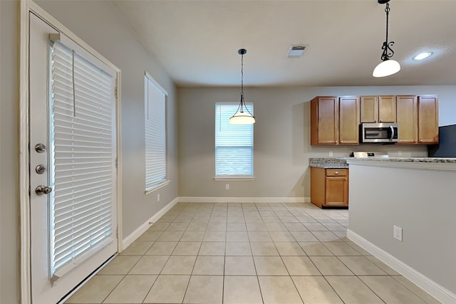 kitchen featuring decorative light fixtures, fridge, and light tile patterned flooring