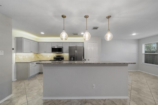 kitchen featuring light stone countertops, a center island, decorative light fixtures, and appliances with stainless steel finishes