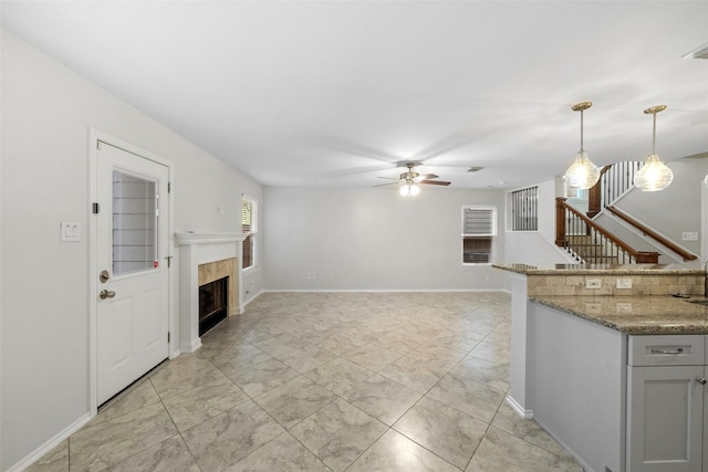 kitchen featuring light stone countertops, ceiling fan, and pendant lighting