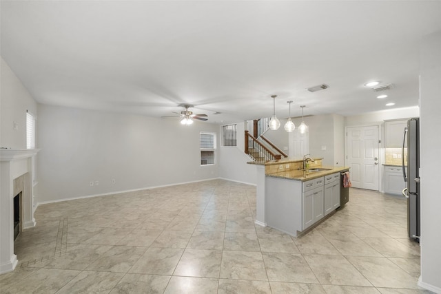 kitchen featuring sink, hanging light fixtures, ceiling fan, light stone countertops, and appliances with stainless steel finishes