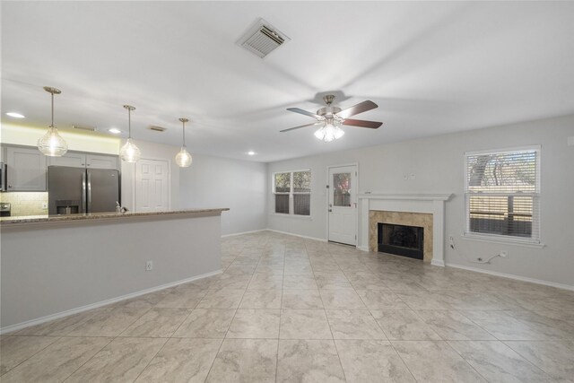 unfurnished living room with a wealth of natural light and ceiling fan