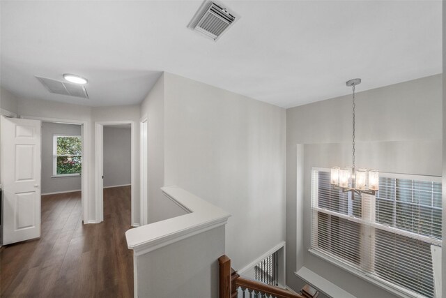 corridor with dark hardwood / wood-style flooring and an inviting chandelier