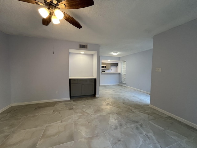 unfurnished living room featuring ceiling fan and a textured ceiling