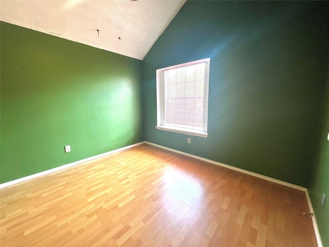 unfurnished room featuring hardwood / wood-style floors and vaulted ceiling