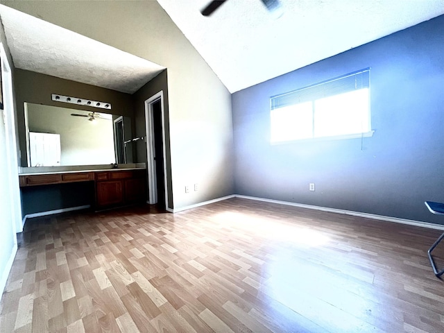 unfurnished bedroom featuring ceiling fan, built in desk, lofted ceiling, and hardwood / wood-style flooring