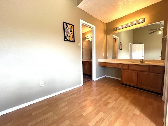 bathroom with hardwood / wood-style floors, ceiling fan, sink, and a textured ceiling