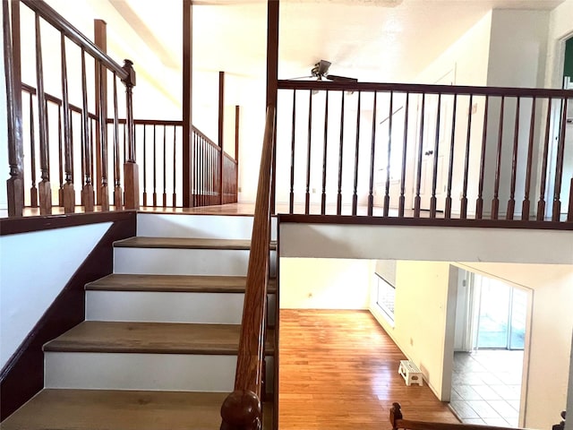 stairs with wood-type flooring and ceiling fan