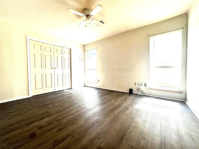 unfurnished bedroom featuring ceiling fan, ornamental molding, dark wood-type flooring, and a closet