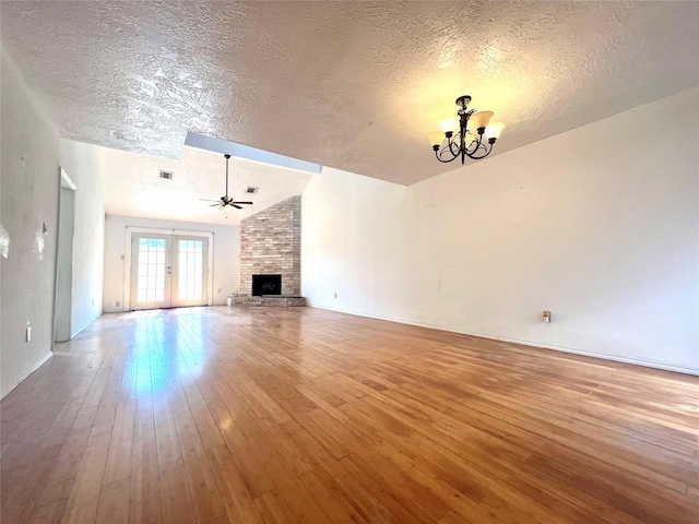 unfurnished living room with vaulted ceiling, french doors, wood-type flooring, and a textured ceiling