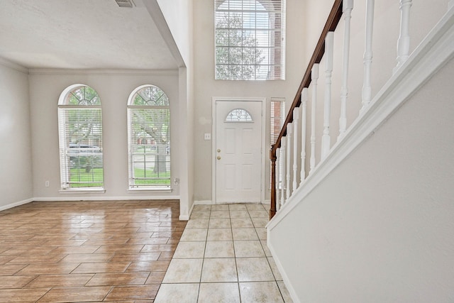 foyer entrance with crown molding and a textured ceiling