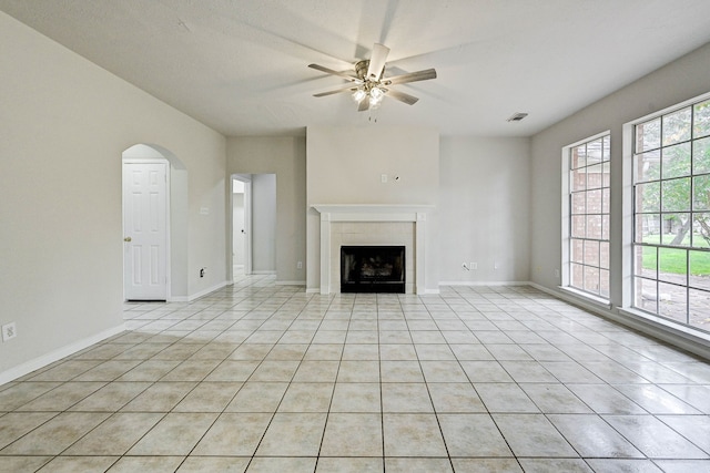 unfurnished living room featuring ceiling fan, a fireplace, and light tile patterned floors