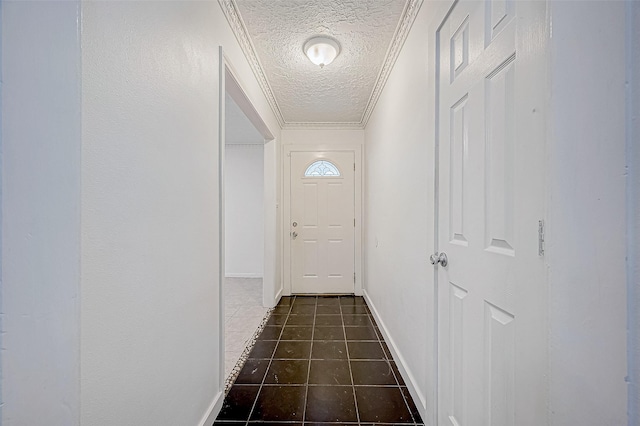 corridor with a textured ceiling, dark tile patterned floors, and crown molding