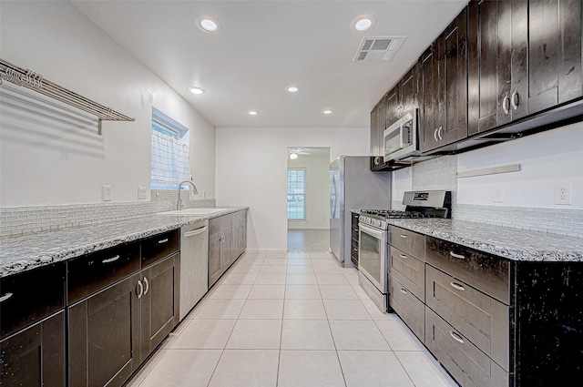 kitchen featuring ceiling fan, sink, light stone counters, light tile patterned flooring, and appliances with stainless steel finishes