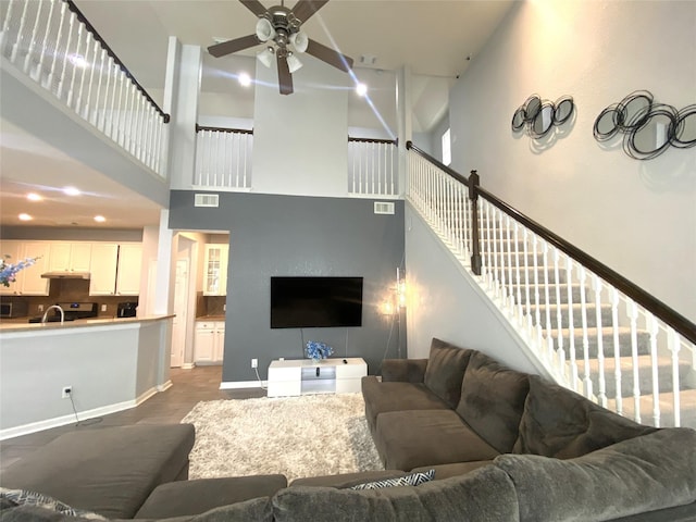 living room featuring ceiling fan, a towering ceiling, and dark wood-type flooring