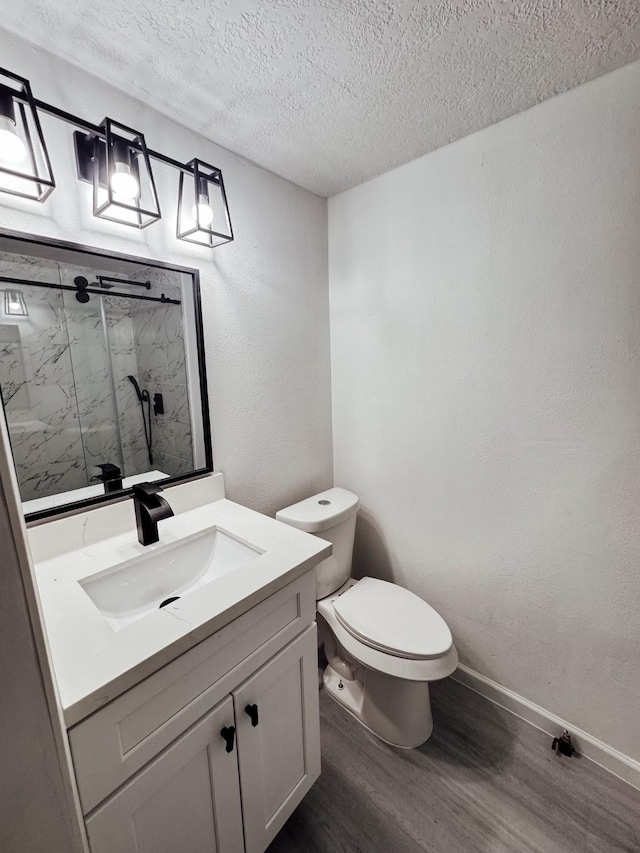 bathroom with walk in shower, a textured ceiling, vanity, wood-type flooring, and toilet