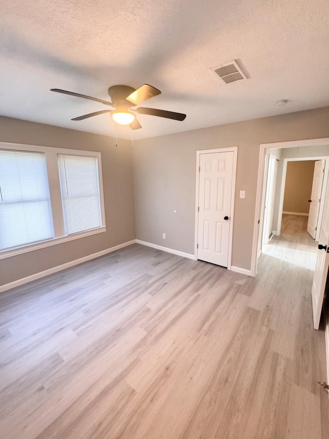 empty room featuring ceiling fan, light hardwood / wood-style floors, and a textured ceiling